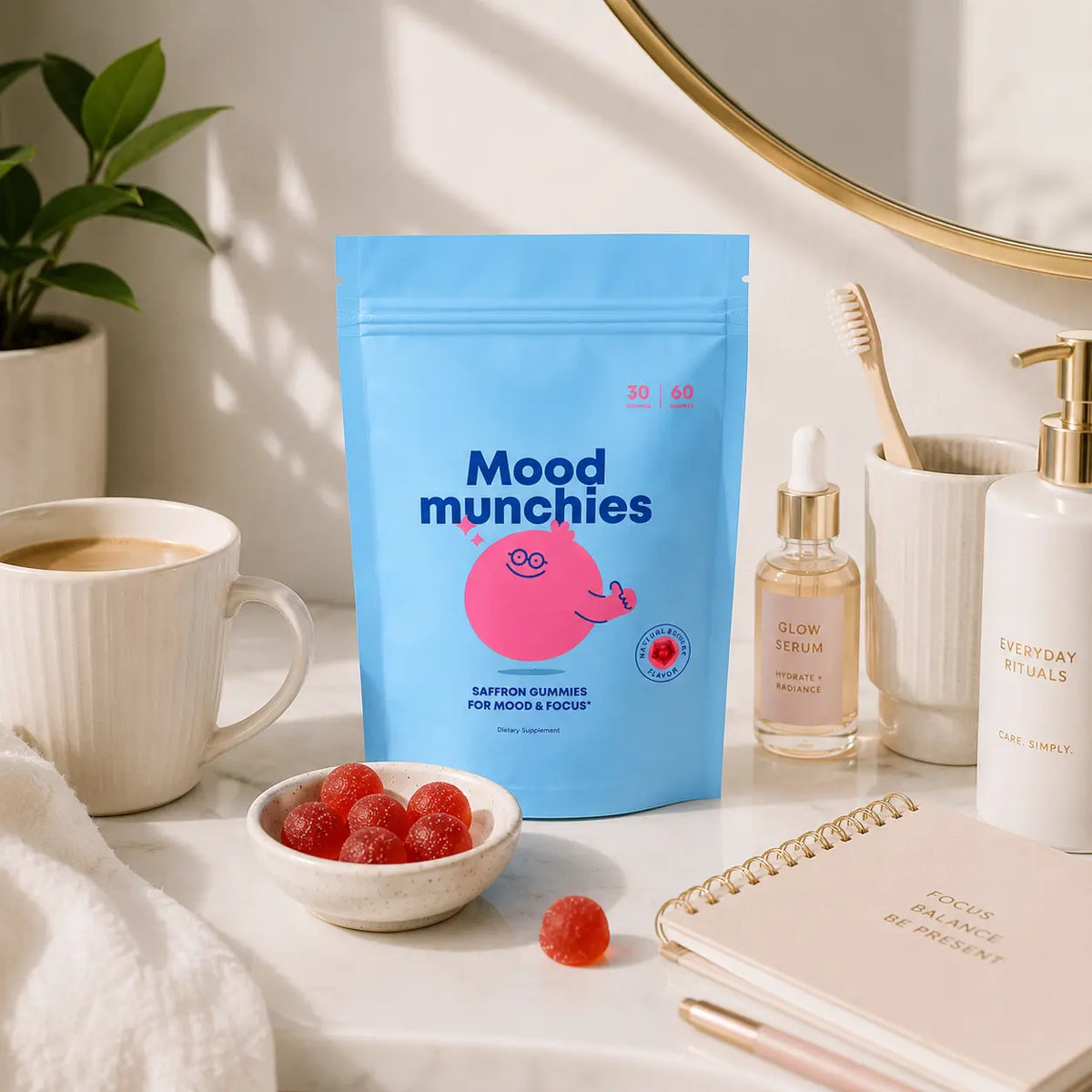 A blue stand-up pouch of Mood munchies gummy candies stands on a white marble surface in a styled bathroom or vanity scene. The pouch has a pink cartoon character and the text 'Mood munchies' and 'Saffron Gummies for Mood & Focus.
